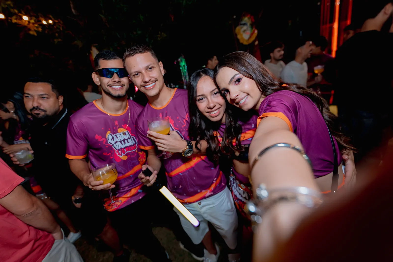 Grupo de formandos com a camisa da festa tirando selfie à noite.
