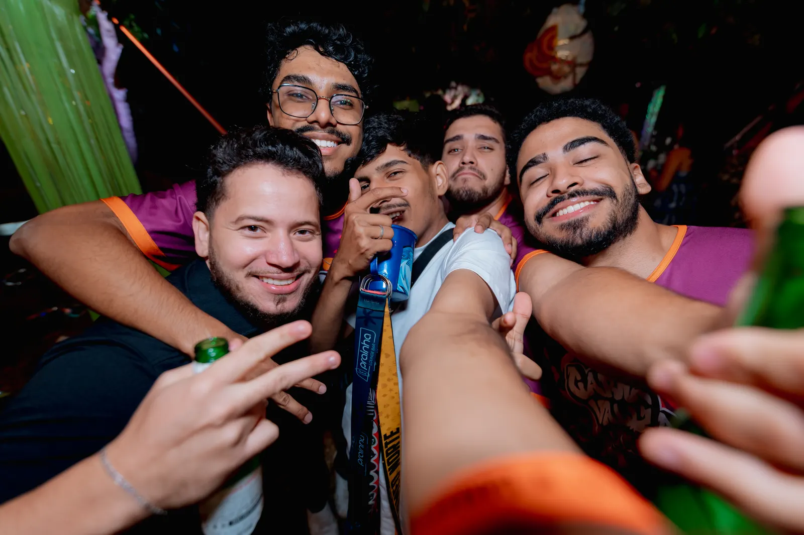 Formandos abraçados tirando uma selfie coletiva e sorrindo na festa.