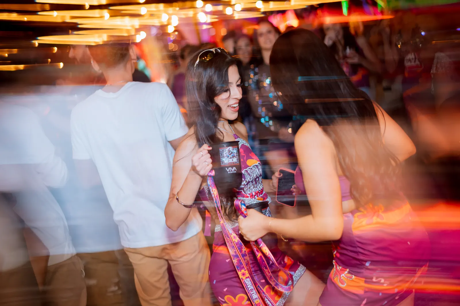 Formanda com a roupa da festa dançando entre os convidados, com luzes em movimento.