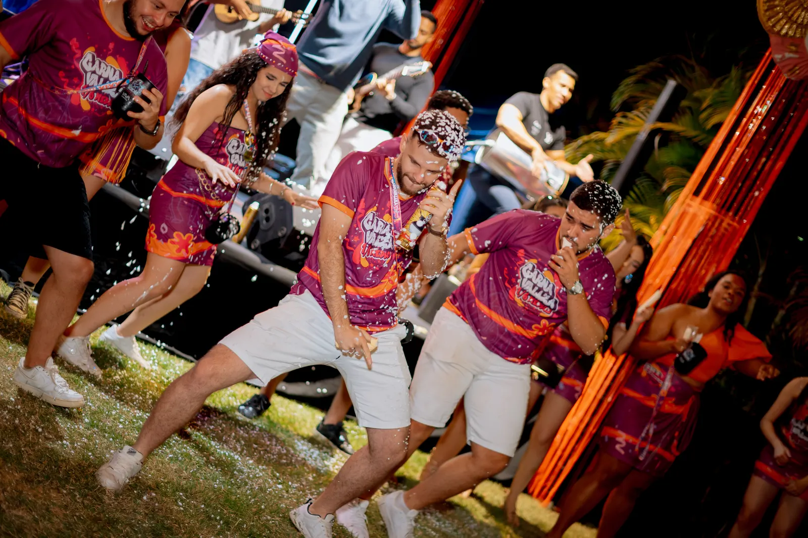 Formandos com a camisa da festa dançando no gramado com confete no ar.