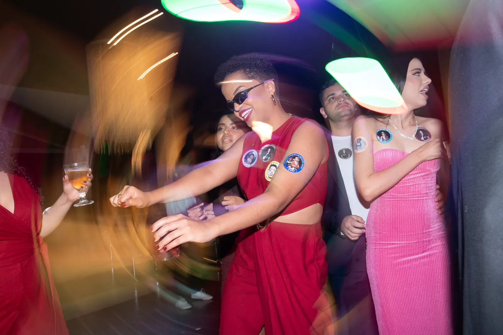 Formanda de roupa vermelha dançando na pista, com as luzes da festa em movimento.