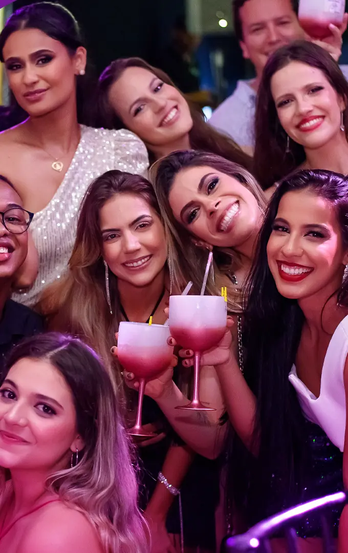 Grupo de formandas e convidados brinda com taças no baile de gala unificado.